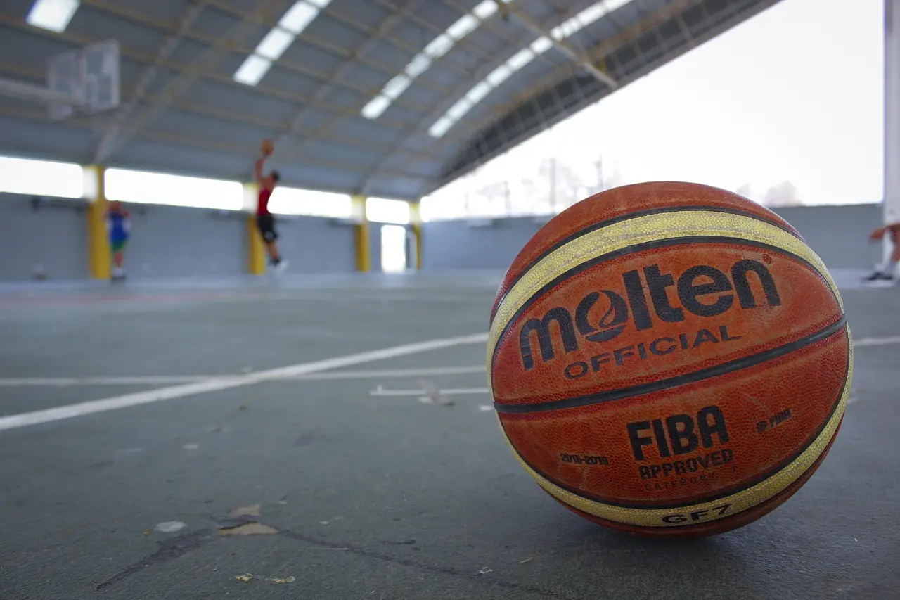 Basketball på banen med spillere i baggrunden